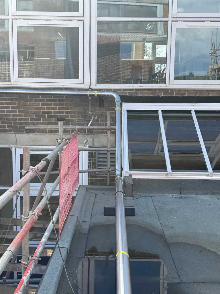 Stainless-steel gas pipe descending from the roof beside classroom windows at Faringdon Community College
