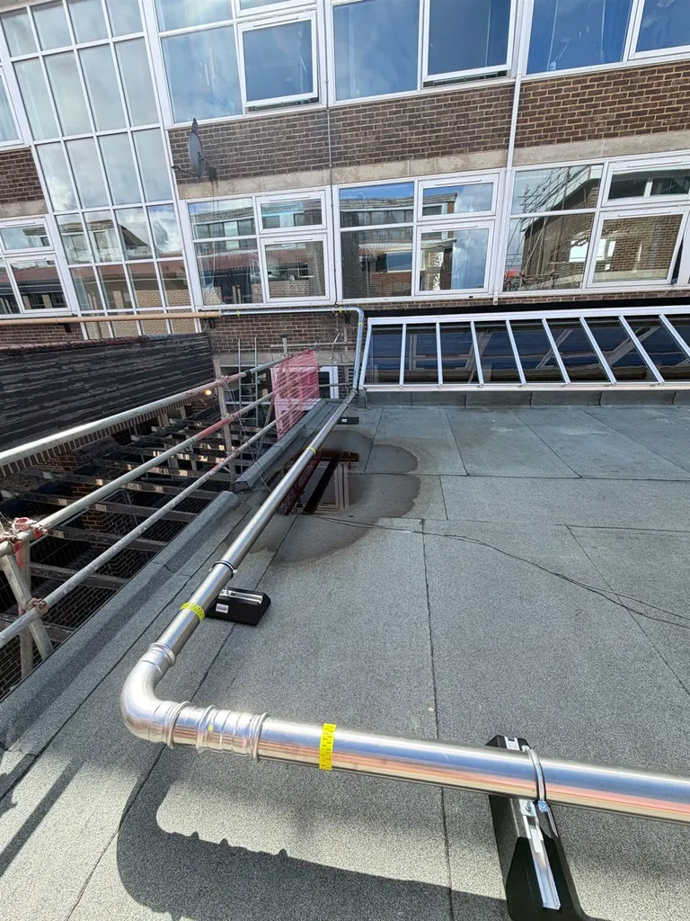 Supported stainless-steel gas main turning around the finished roof edge at Faringdon Community College