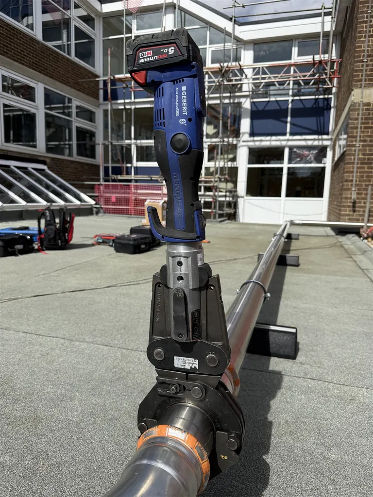 Press tool attached to a stainless-steel rooftop gas-main fitting at Faringdon Community College