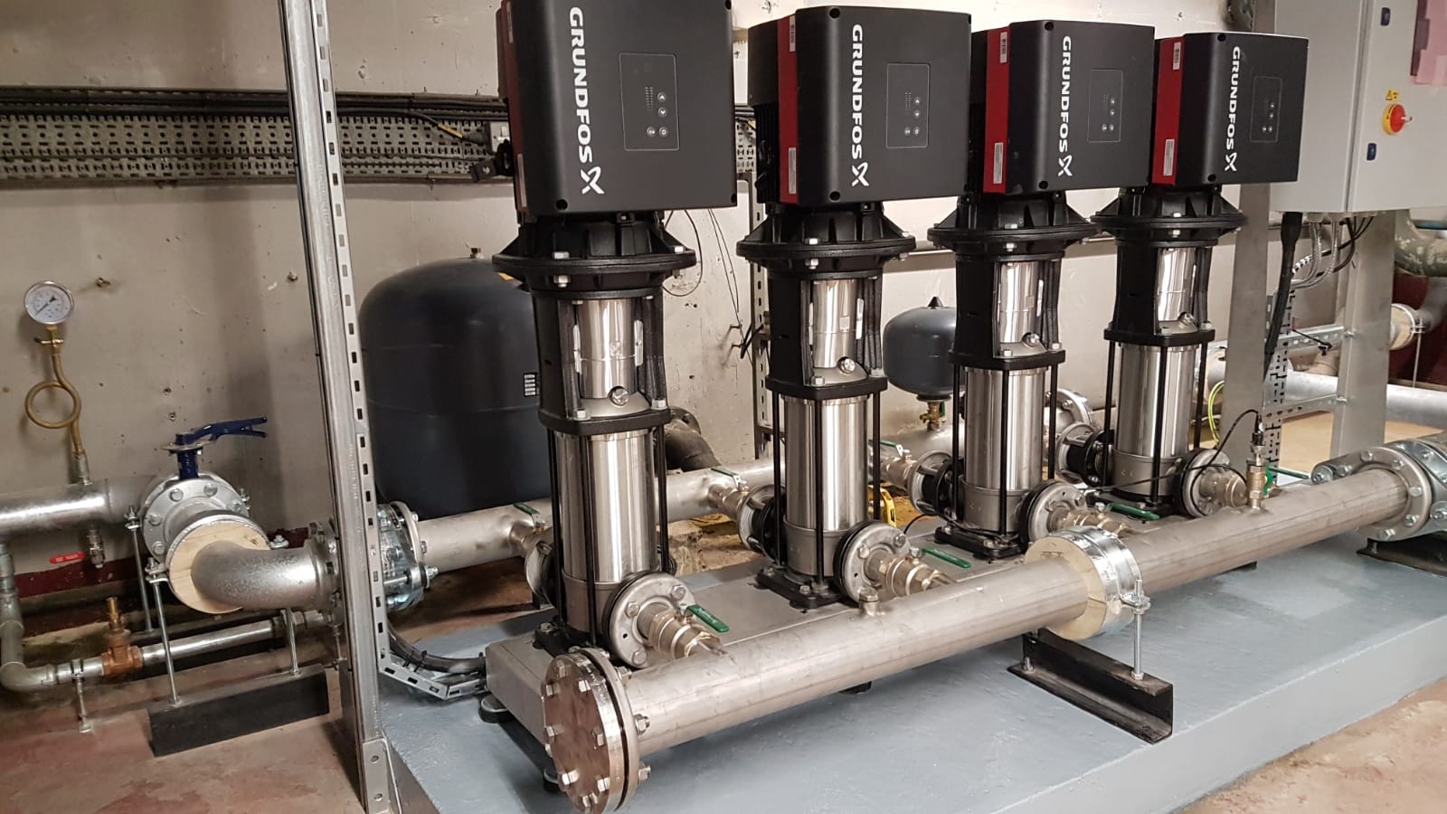 Installed Grundfos Hydro MPC-E cold-water booster set connected to plant-room pipework