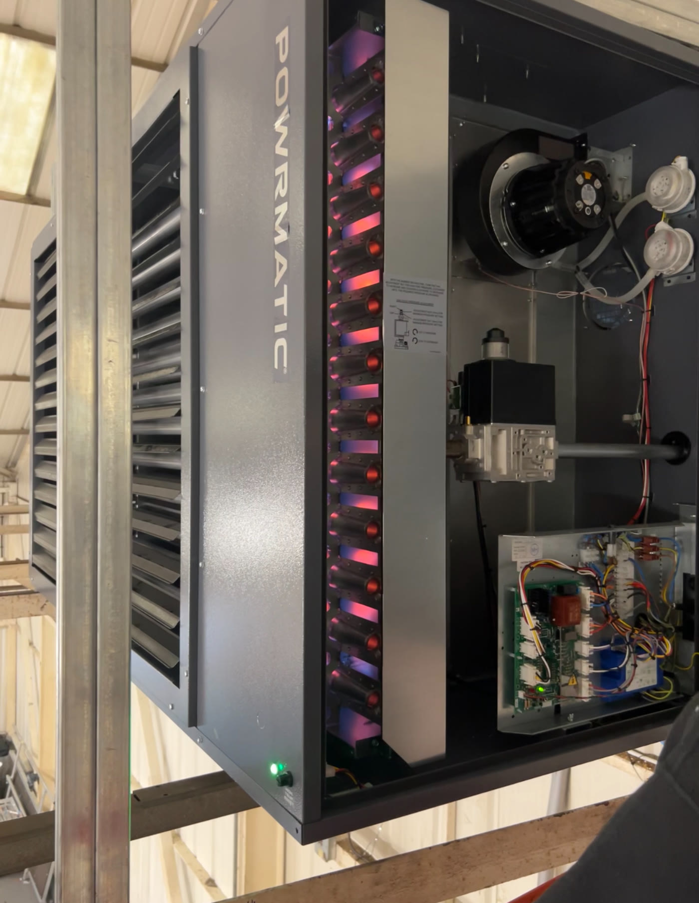 Powrmatic warehouse warm-air heater operating with its casing open for servicing
