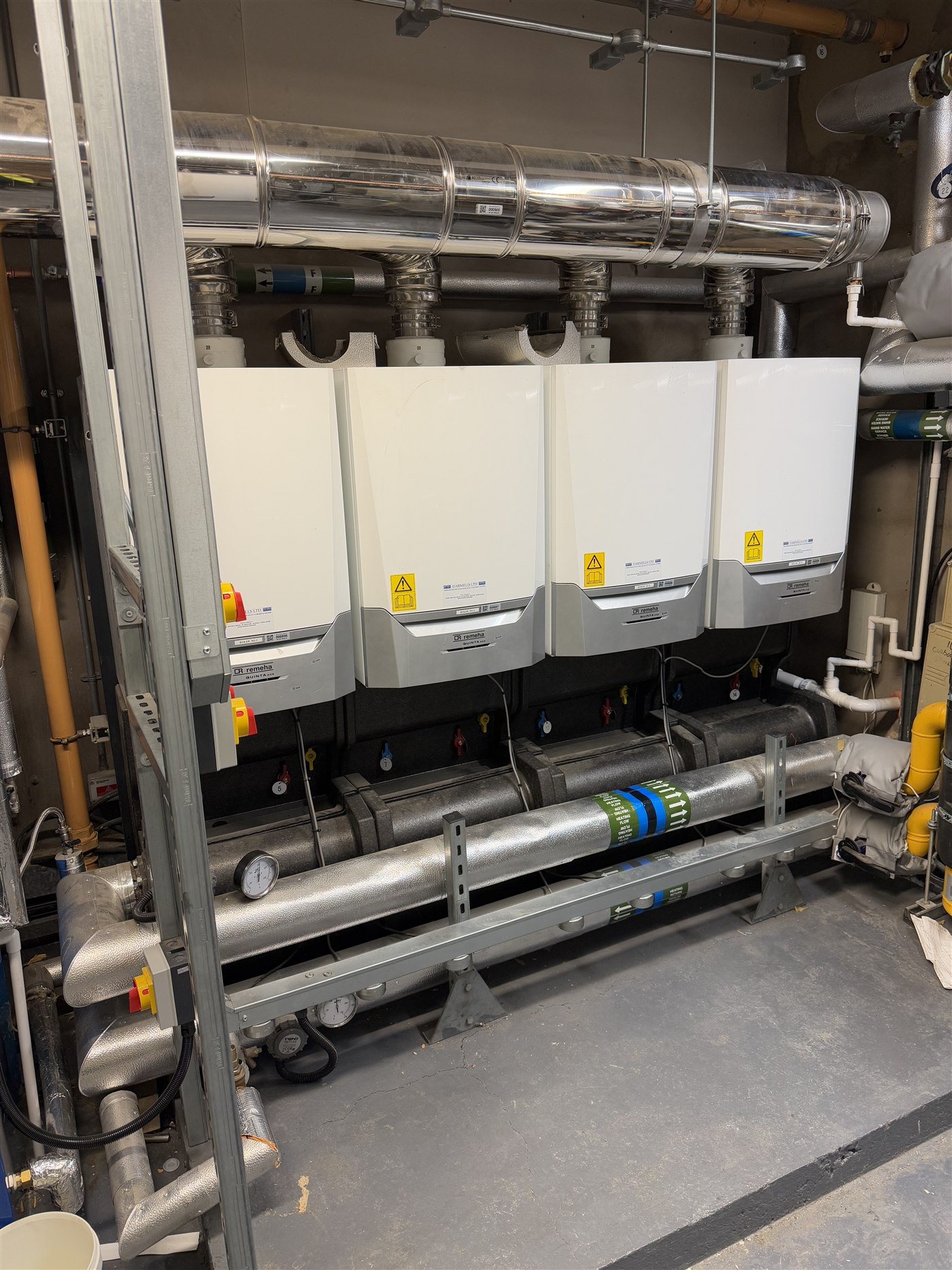 Bank of four Remeha commercial boilers with common flue and insulated pipework